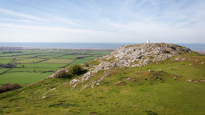 View towards the trig point on Graig Fawr, with expansive views overlooking fields and towns in the distance.